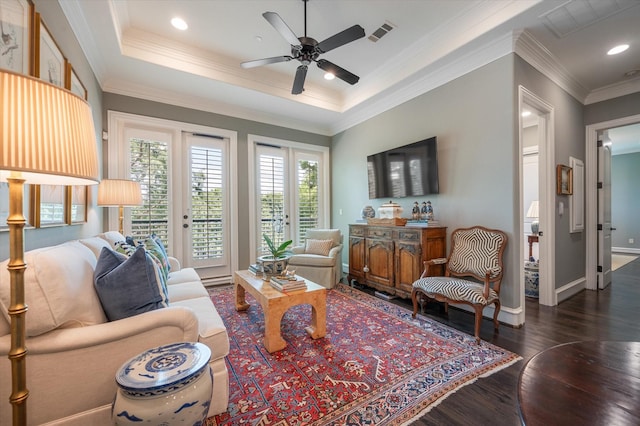 living room featuring ceiling fan, french doors, a raised ceiling, dark hardwood / wood-style flooring, and ornamental molding