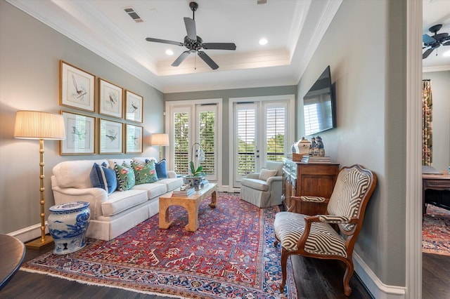 living room featuring ceiling fan, french doors, a tray ceiling, hardwood / wood-style floors, and ornamental molding