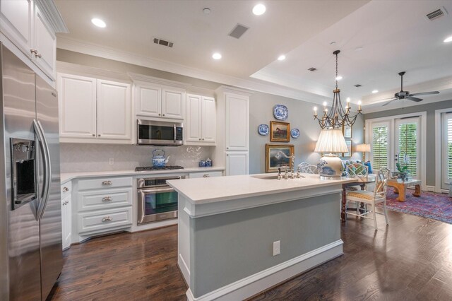 kitchen with white cabinetry, hanging light fixtures, stainless steel appliances, and a center island with sink