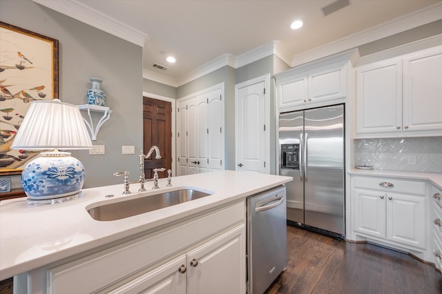 kitchen with appliances with stainless steel finishes, sink, white cabinetry, ornamental molding, and decorative backsplash