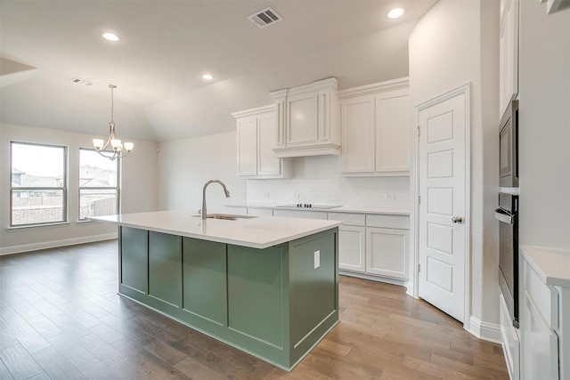 kitchen with pendant lighting, white cabinets, lofted ceiling, black electric stovetop, and sink