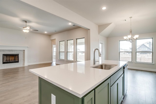 kitchen featuring light hardwood / wood-style floors, pendant lighting, sink, an island with sink, and green cabinetry