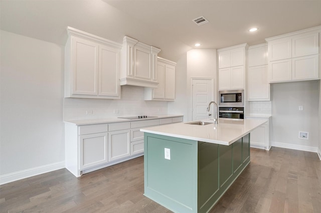 kitchen featuring an island with sink, sink, stainless steel oven, black electric cooktop, and built in microwave