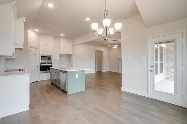 kitchen with sink, hanging light fixtures, an island with sink, stainless steel appliances, and white cabinets