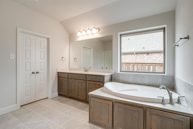 bathroom with a washtub, vanity, lofted ceiling, and tile patterned flooring