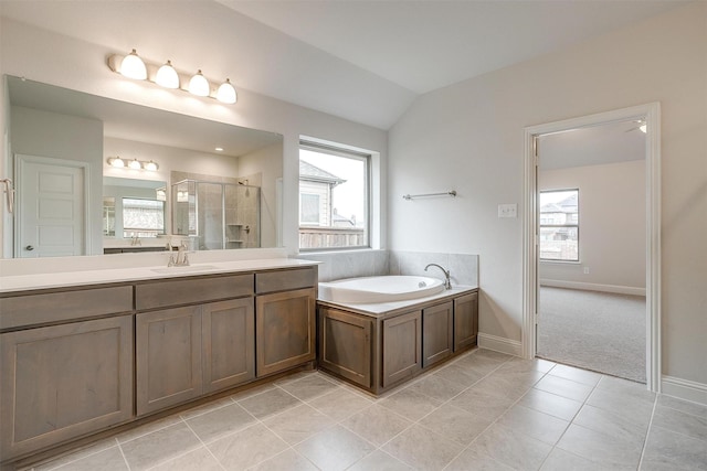 bathroom with a healthy amount of sunlight, vaulted ceiling, vanity, and independent shower and bath