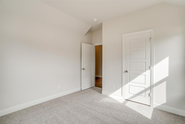 unfurnished bedroom with light colored carpet and vaulted ceiling