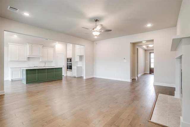 unfurnished living room featuring ceiling fan, light hardwood / wood-style floors, and sink