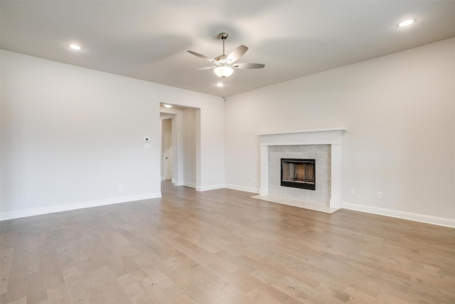 unfurnished living room with ceiling fan, a fireplace, and light hardwood / wood-style floors