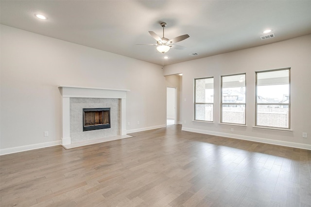 unfurnished living room featuring ceiling fan, light hardwood / wood-style floors, and a tile fireplace