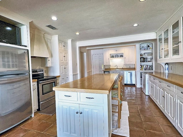 kitchen featuring white cabinets, stainless steel appliances, a kitchen island, and sink