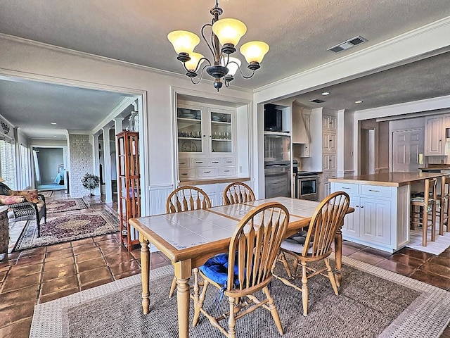 dining space with dark tile patterned floors, ornamental molding, a textured ceiling, and a notable chandelier