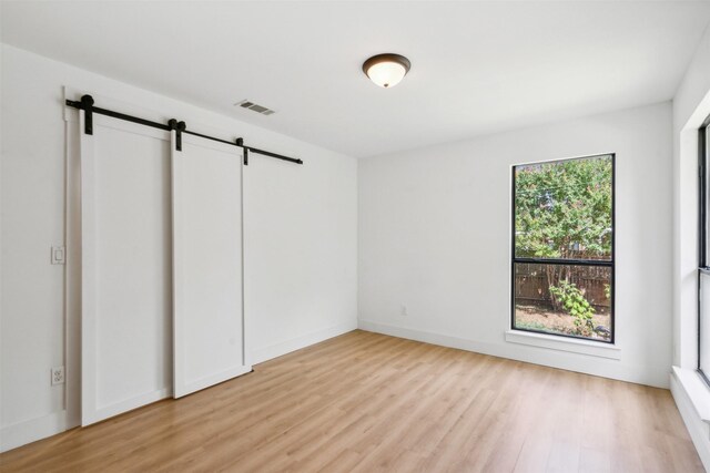 2905 Bilglade Rd, Fort Worth, TX 76133 - unfurnished bedroom featuring a barn door and light wood-style floors