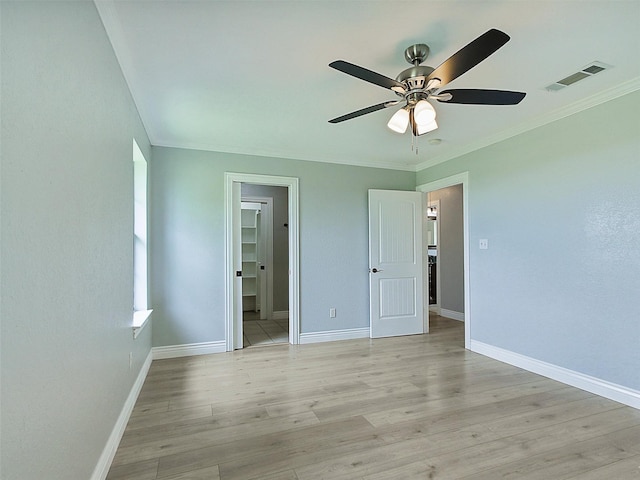 unfurnished bedroom featuring light hardwood / wood-style floors, a spacious closet, ceiling fan, and ornamental molding