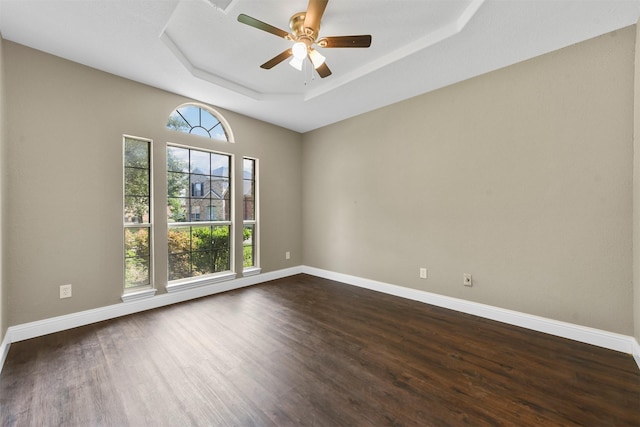 unfurnished room featuring dark hardwood / wood-style floors, ceiling fan, and a tray ceiling