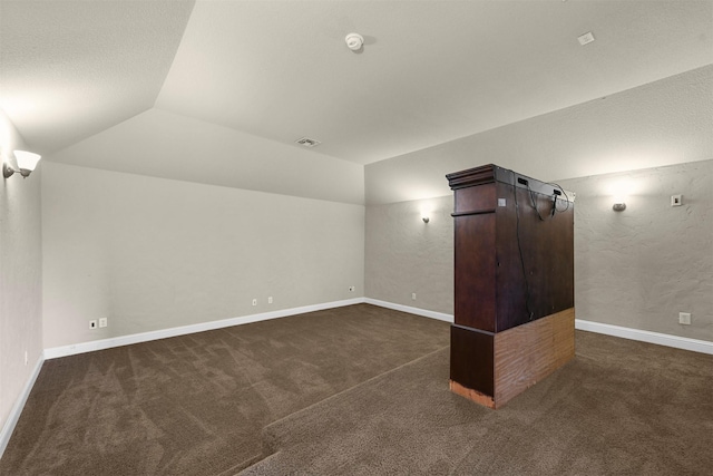 additional living space with dark carpet and vaulted ceiling