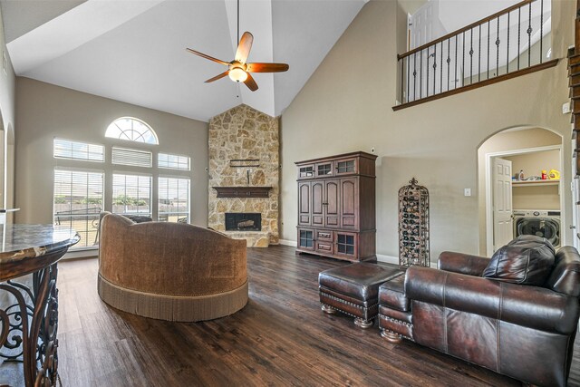 living room with dark hardwood / wood-style flooring, ceiling fan, high vaulted ceiling, a fireplace, and washer / dryer