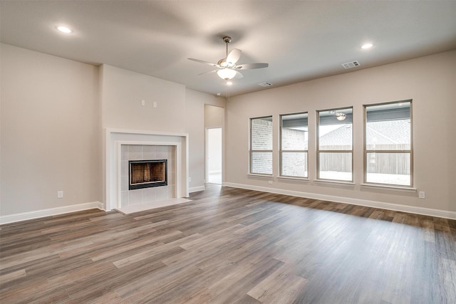 unfurnished living room with ceiling fan, a tile fireplace, and hardwood / wood-style floors