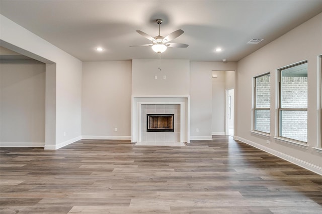 unfurnished living room featuring ceiling fan, wood-type flooring, and a fireplace