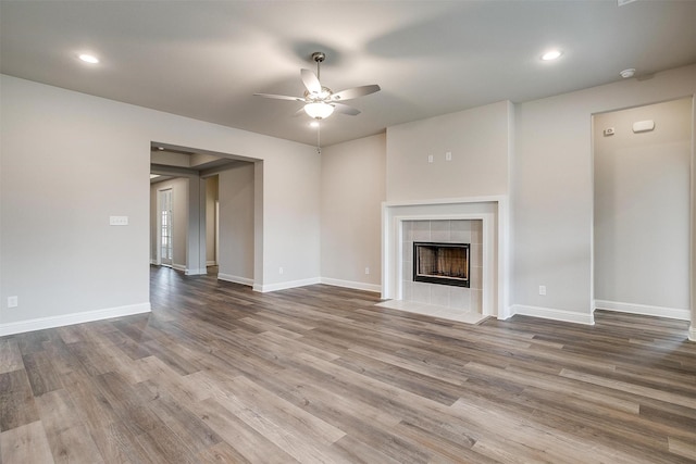 unfurnished living room featuring ceiling fan, hardwood / wood-style floors, and a tile fireplace