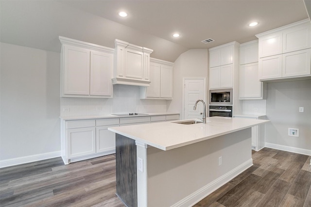 kitchen with wall oven, sink, white cabinetry, and a center island with sink