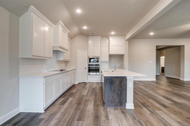 kitchen featuring backsplash, white cabinetry, stainless steel oven, and built in microwave