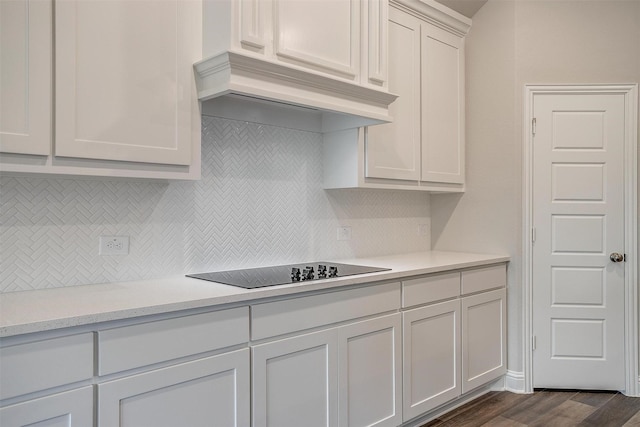 kitchen featuring custom exhaust hood, black electric cooktop, tasteful backsplash, dark wood-type flooring, and white cabinets