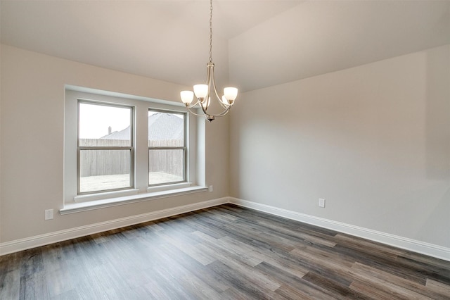 spare room featuring dark wood-type flooring, an inviting chandelier, and lofted ceiling