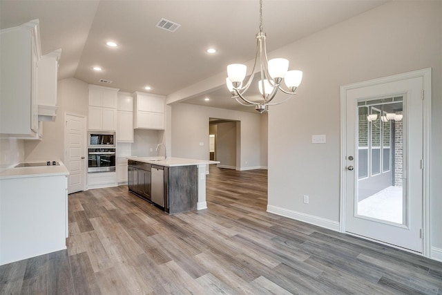 kitchen with black appliances, white cabinetry, sink, hanging light fixtures, and a center island with sink