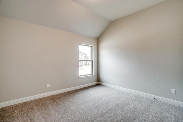 carpeted spare room with vaulted ceiling