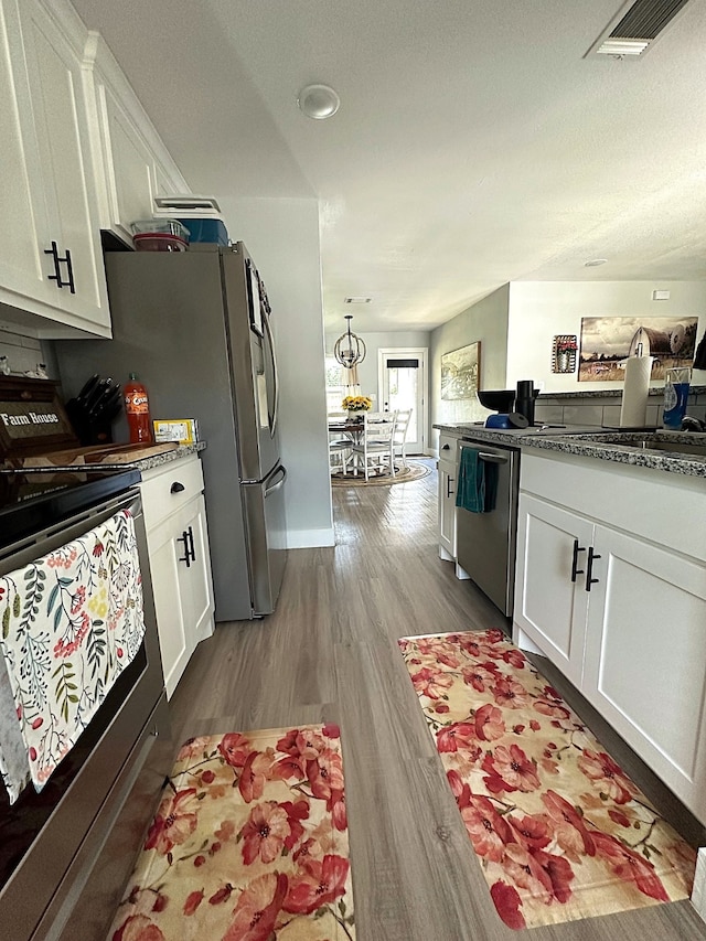 kitchen with dark stone counters, range with electric cooktop, dishwasher, wood-type flooring, and white cabinetry