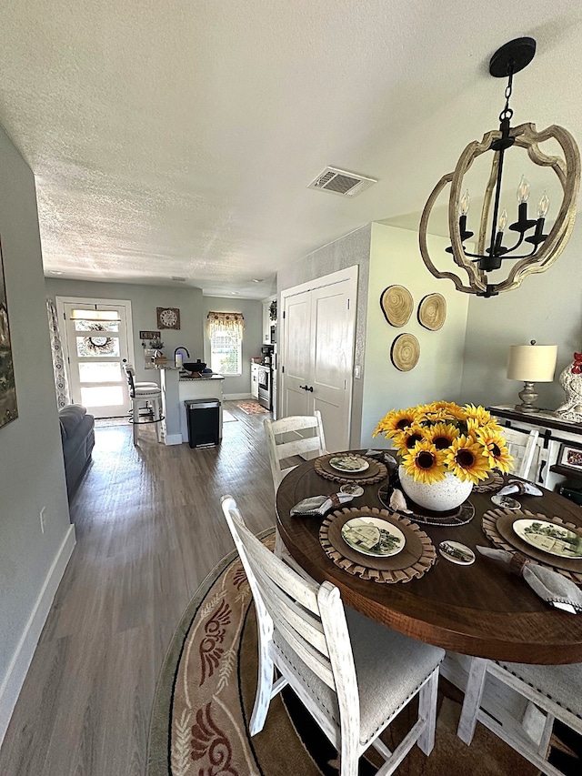 dining room with an inviting chandelier, a textured ceiling, and wood-type flooring