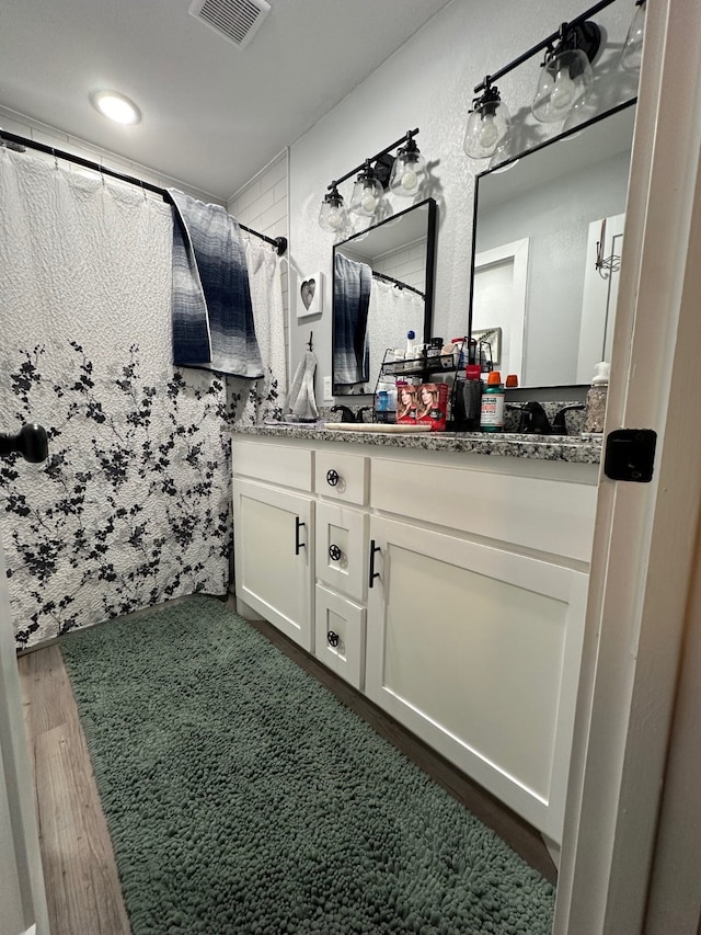 bathroom with hardwood / wood-style floors and vanity with extensive cabinet space