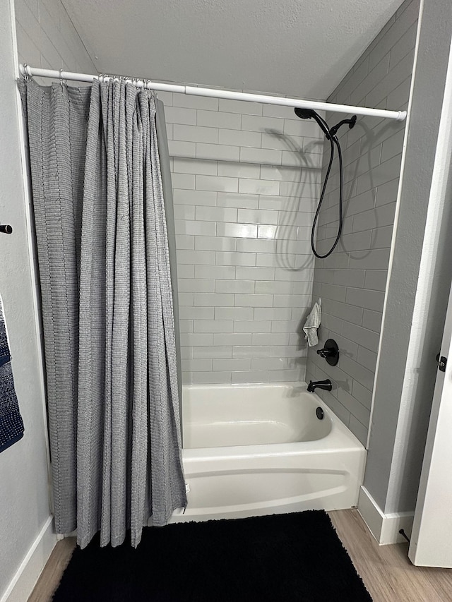 bathroom featuring wood-type flooring, a textured ceiling, and shower / tub combo with curtain