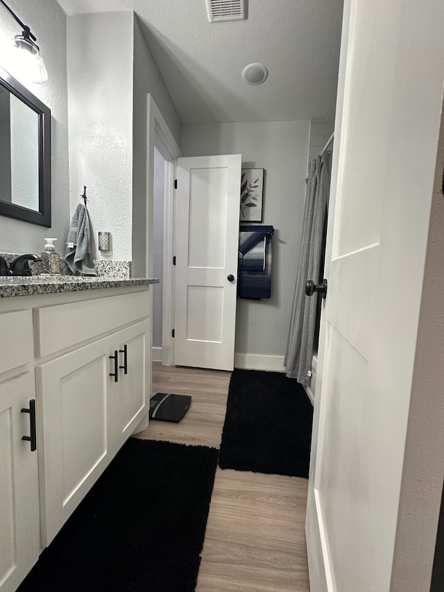 bathroom featuring hardwood / wood-style flooring, vanity, and a textured ceiling