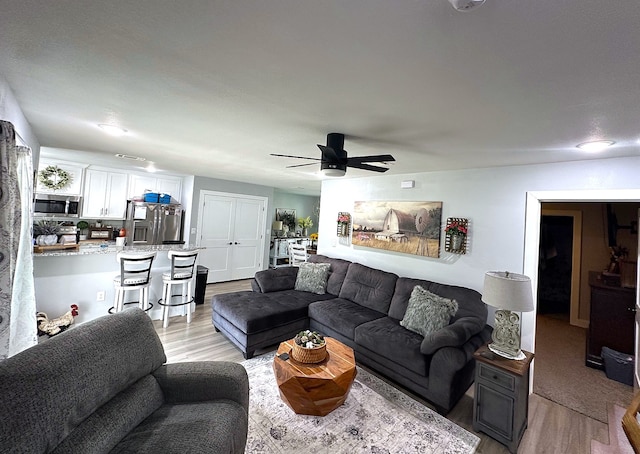 living room with light wood-type flooring and ceiling fan