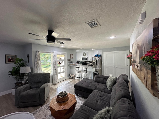 living room featuring ceiling fan, a textured ceiling, and hardwood / wood-style flooring