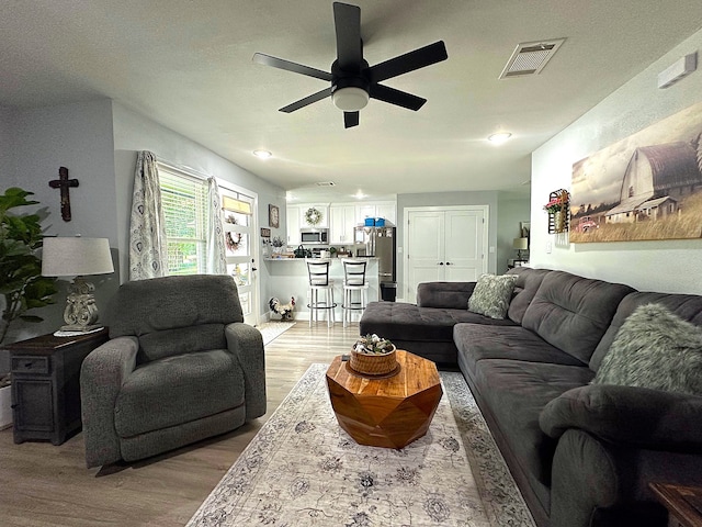 living room featuring ceiling fan and light hardwood / wood-style flooring