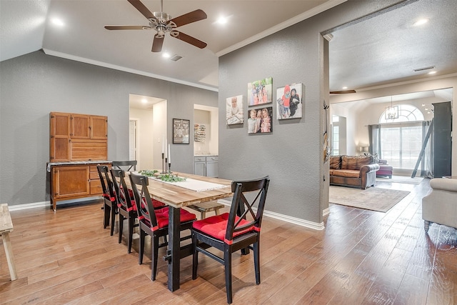 dining area with ceiling fan with notable chandelier, vaulted ceiling, light hardwood / wood-style flooring, and ornamental molding