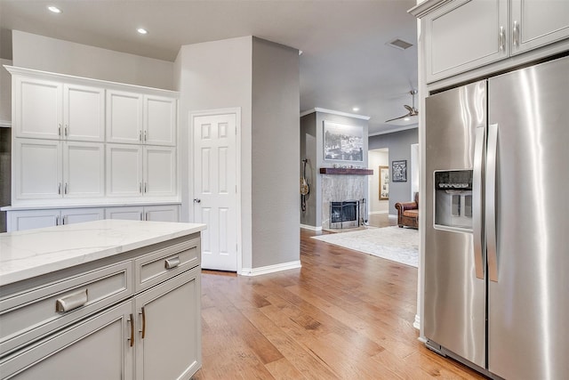 kitchen with light hardwood / wood-style flooring, light stone counters, white cabinetry, and stainless steel fridge with ice dispenser