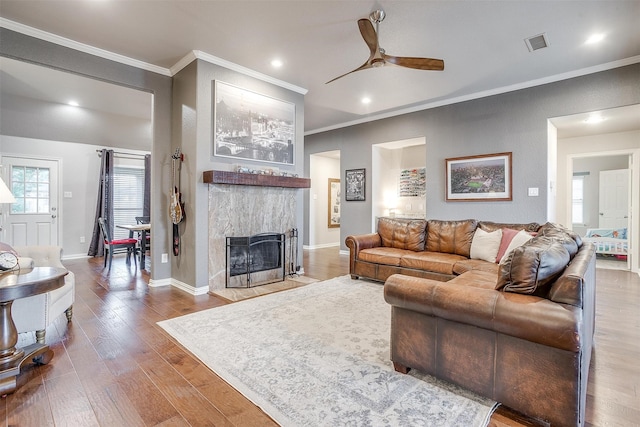 living room with ceiling fan, hardwood / wood-style flooring, a fireplace, and crown molding