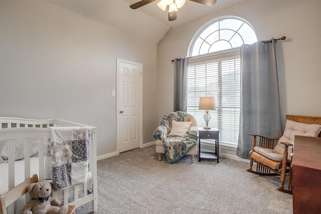 carpeted bedroom with ceiling fan, a crib, and vaulted ceiling