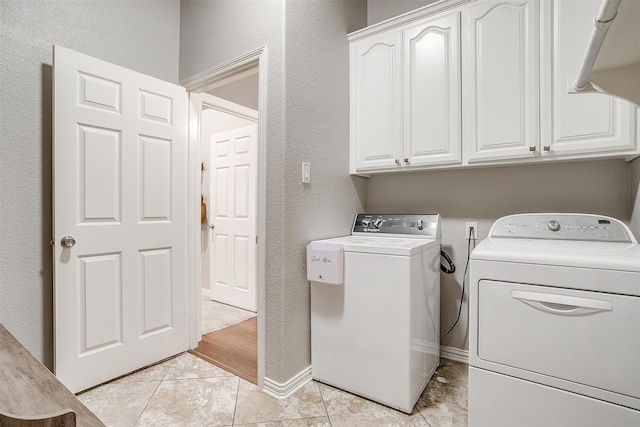 washroom with cabinet space, baseboards, washer and clothes dryer, and light tile patterned flooring