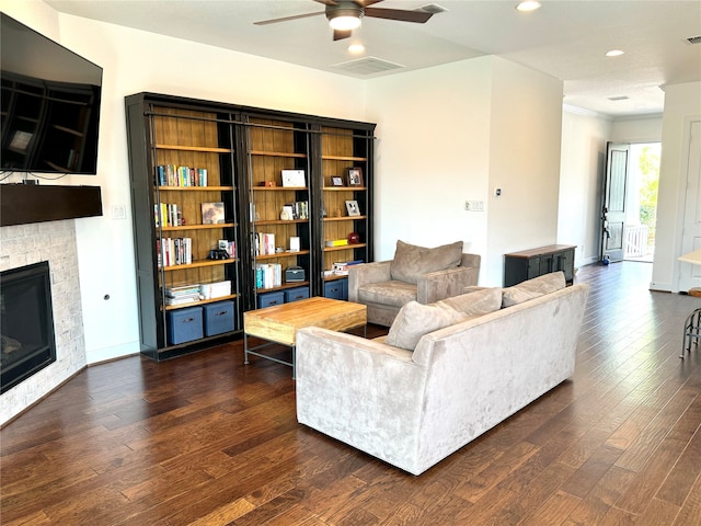 living room featuring ceiling fan, a fireplace, and dark wood-type flooring