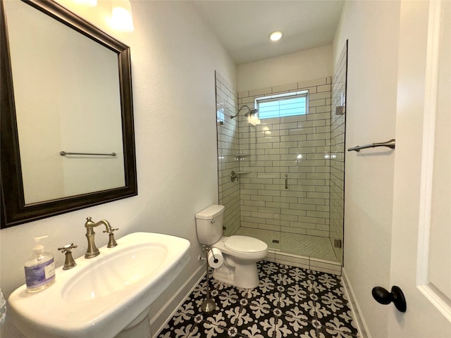 bathroom featuring tile patterned floors, sink, a tile shower, and toilet