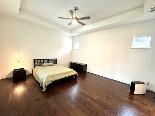 bedroom with dark hardwood / wood-style floors, a raised ceiling, and ceiling fan