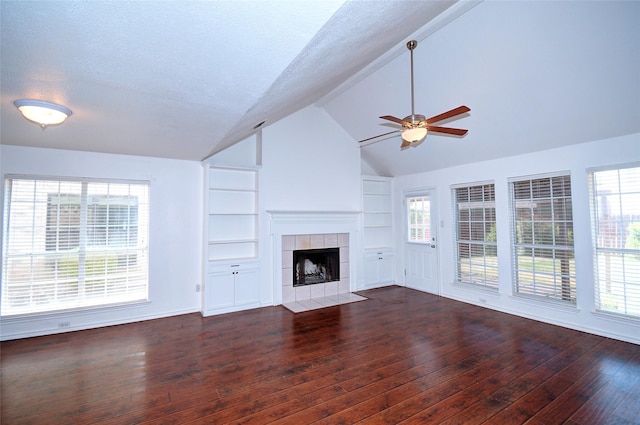 unfurnished living room with a tile fireplace, built in shelves, dark hardwood / wood-style floors, and ceiling fan