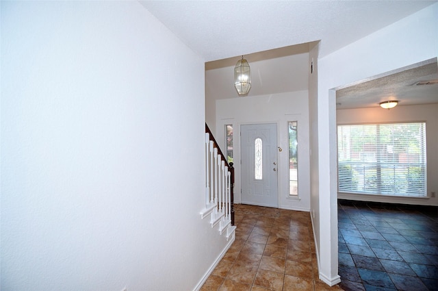 foyer entrance with tile patterned flooring and a textured ceiling