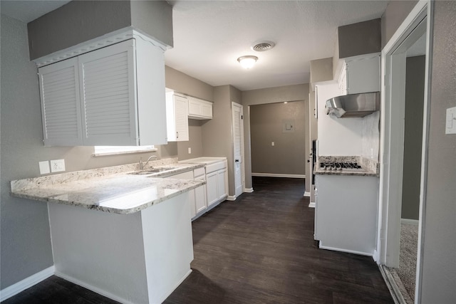 kitchen featuring light stone countertops, dark hardwood / wood-style flooring, extractor fan, sink, and white cabinets