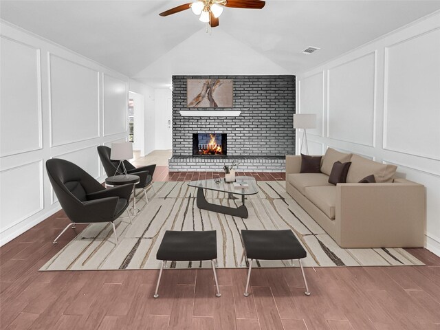 living room featuring brick wall, hardwood / wood-style flooring, lofted ceiling, and a brick fireplace